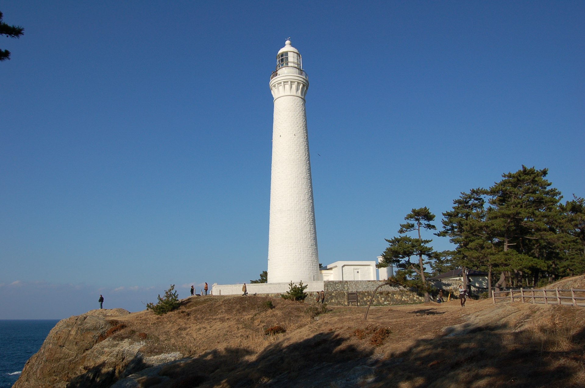 히노미사키 등대는 푸른 해안과 흰 수직선을 보는 장면입니다